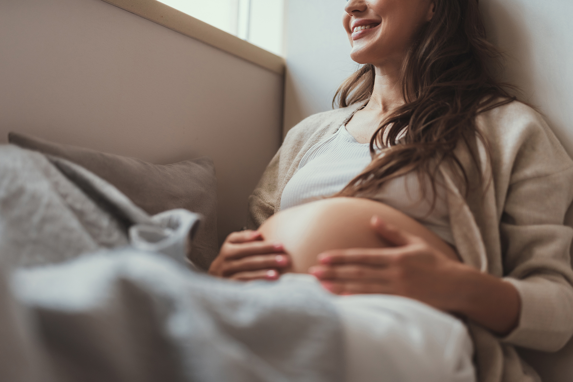 Glad future mom tuching her tummy and smiling
