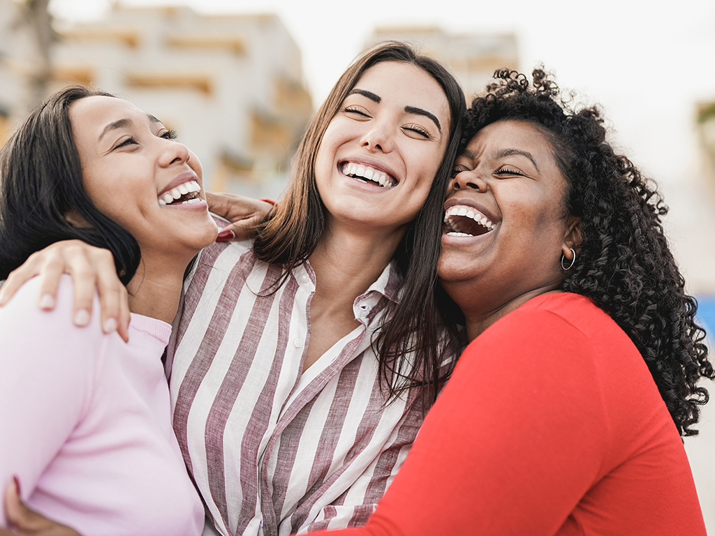 Happy latin women laughing and hugging each other outdoor in the